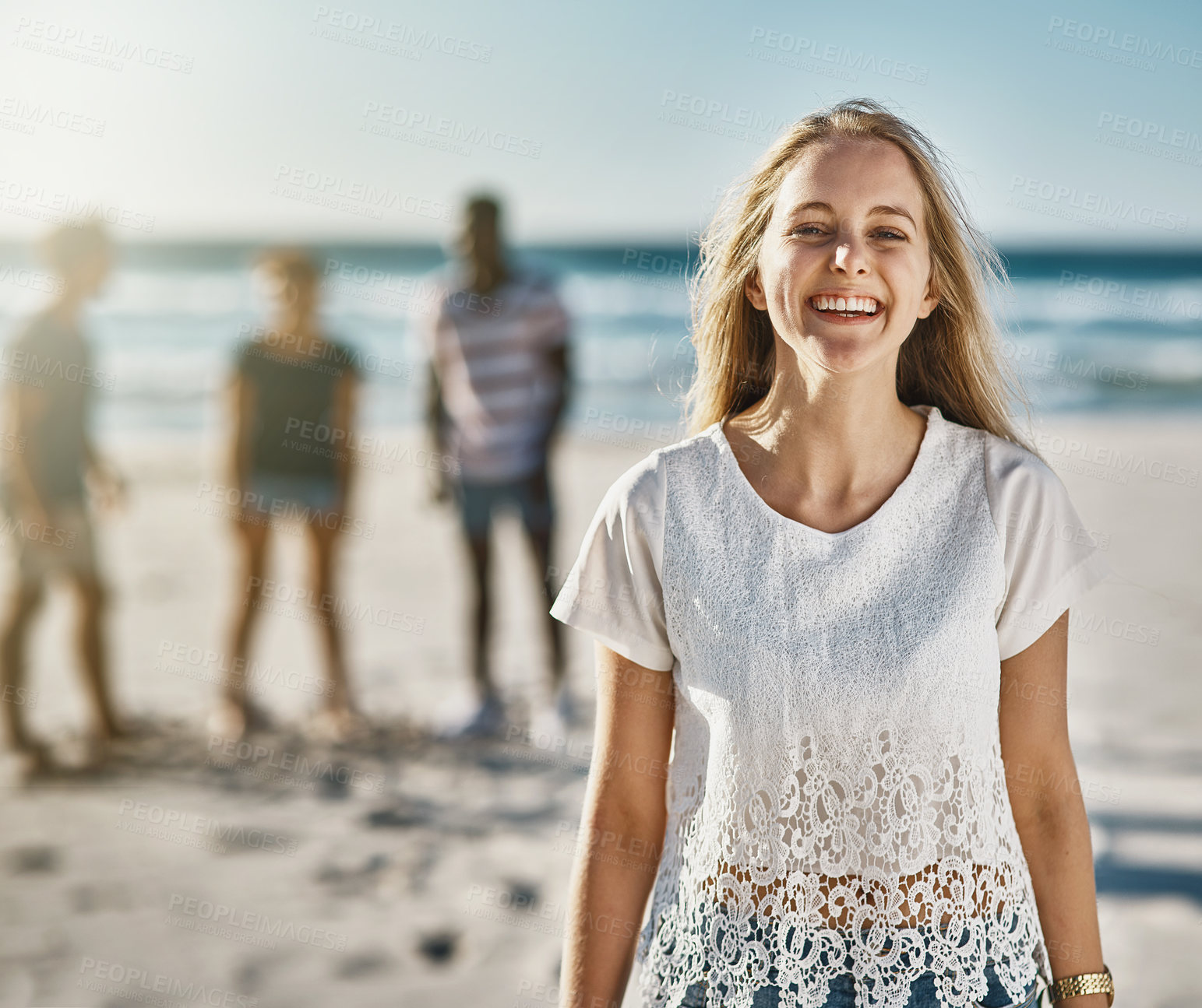 Buy stock photo Portrait of a happy young woman posing on the beach with her friends in the background
