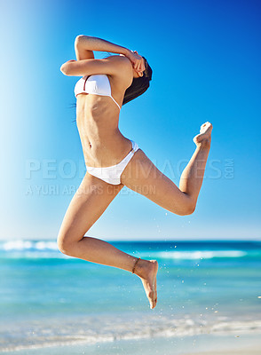 Buy stock photo Shot of a beautiful young woman in a bikini jumping in the air on the beach