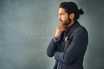 Buy stock photo Studio shot of a stylishly dressed handsome young man standing with his hand on his chin