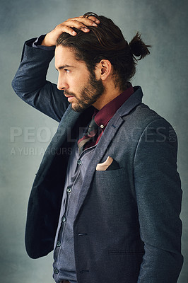 Buy stock photo Studio shot of a stylishly dressed handsome young man standing with his hand in his hair