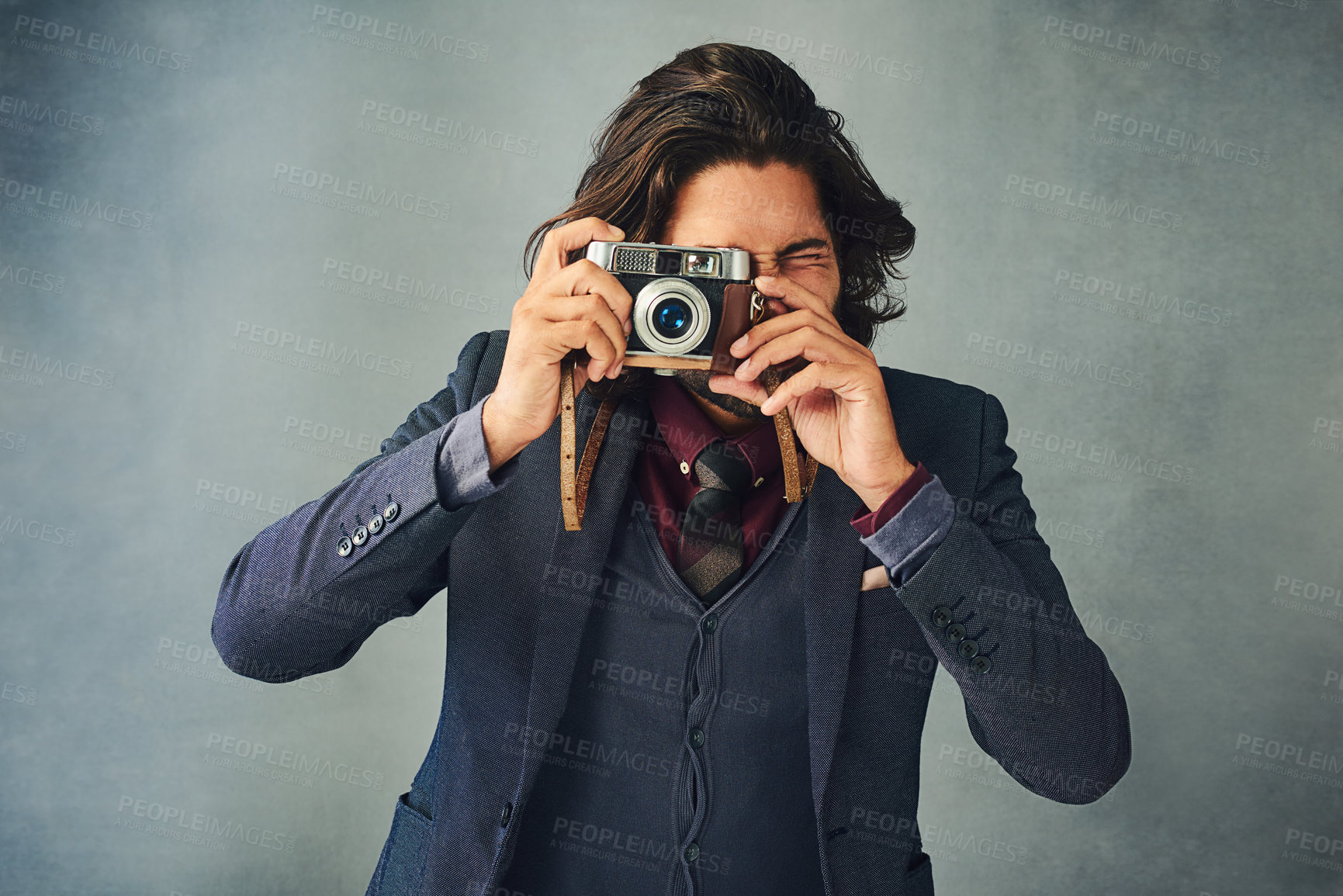 Buy stock photo Studio shot of a stylishly dressed handsome young man taking a picture with a vintage camera