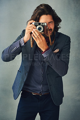 Buy stock photo Studio shot of a stylishly dressed handsome young man taking a picture with a vintage camera