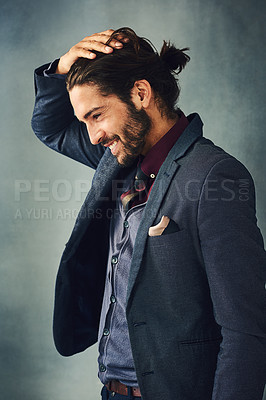 Buy stock photo Studio shot of a stylishly dressed handsome young man standing with his hand in his hair