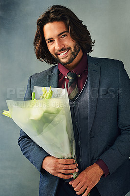 Buy stock photo Studio portrait of a stylishly dressed handsome young man smiling and holding a bouquet of flowers