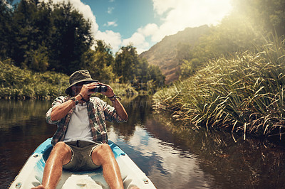 Buy stock photo Cropped shot of a young man looking through his binoculars while enjoying a canoe ride on the lake