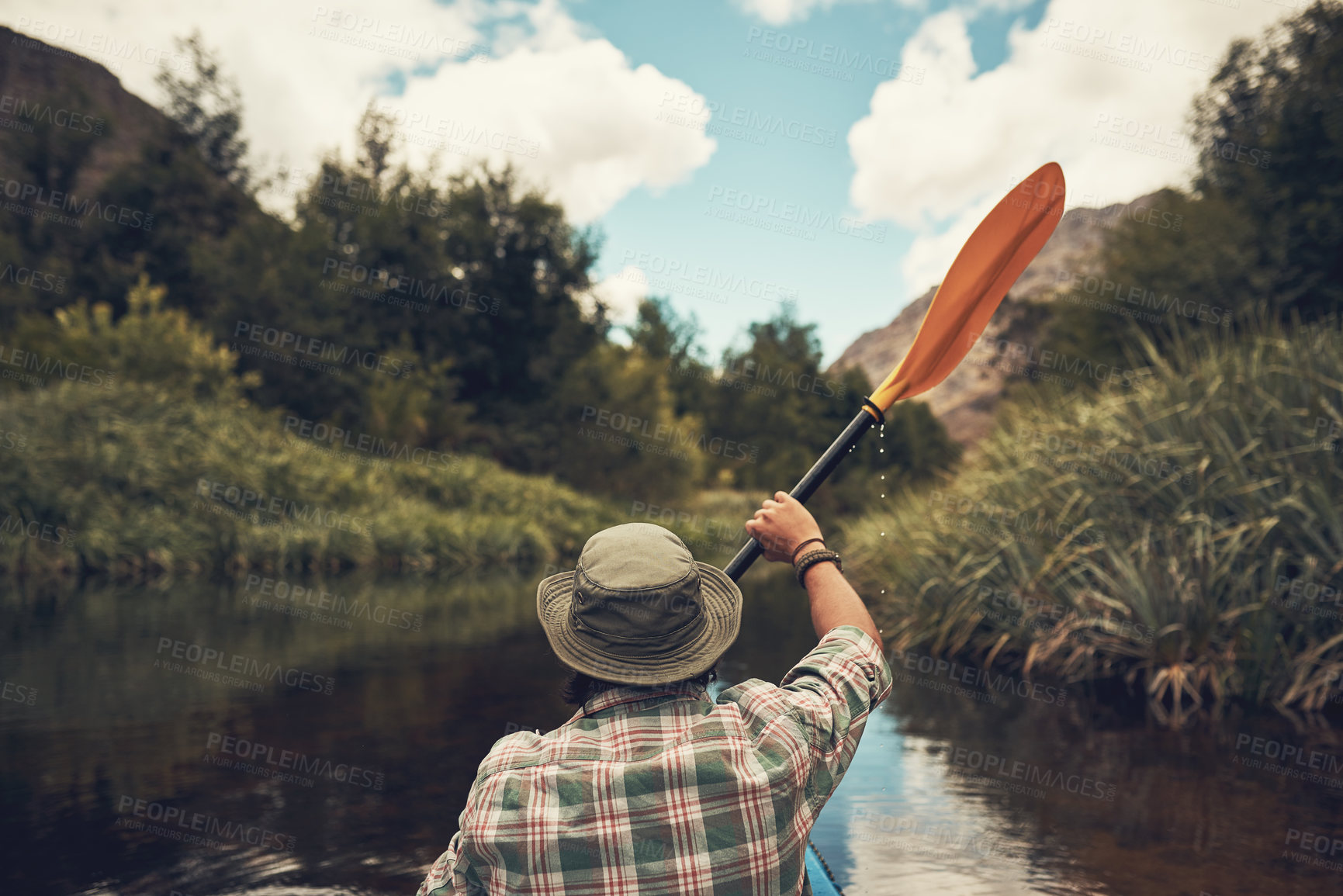 Buy stock photo Landscape, water and person with rowing in river for camping adventure, scenery and exploring nature with blue sky. Kayak, tourist and back in lake for canoeing, summer holiday and fun hobby with hat