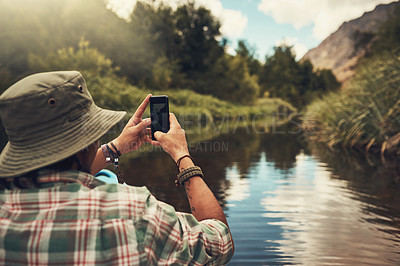 Buy stock photo Back, man and phone for photography on lake with trekking adventure, nature memory and social media post. Male person, photographer and travel with mobile for freedom, journey view and outdoor