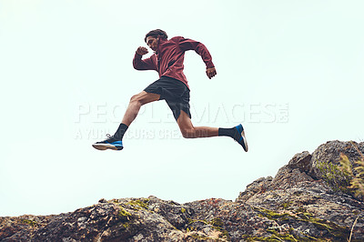 Buy stock photo Shot of a young man jumping in midair while out for a run
