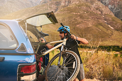 Buy stock photo Cropped shot of a young man taking his bicycle out from the trunk of a car