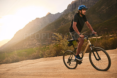 Buy stock photo Shot of a young man cycling along a trail