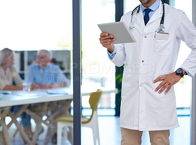 Buy stock photo Cropped shot of a doctor using a digital tablet with two patients sitting in the background