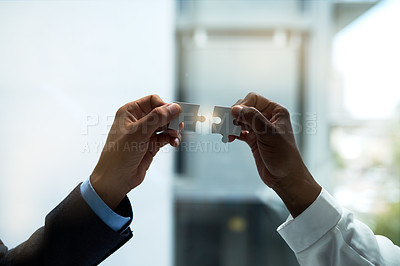 Buy stock photo Closeup shot of two unidentifiable businesspeople holding puzzle pieces together
