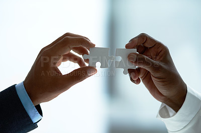 Buy stock photo Closeup shot of two unidentifiable businesspeople holding puzzle pieces together