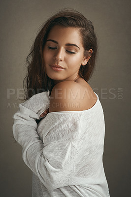 Buy stock photo Shot of a beautiful young woman smiling against a brown background in studio