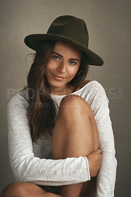 Buy stock photo Portrait of a beautiful young woman sitting on a stool against a brown background in studio