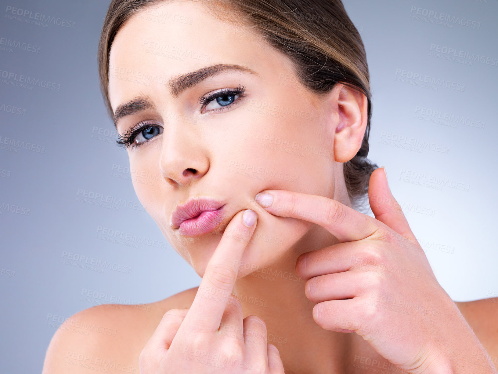 Buy stock photo Cropped shot of a young woman squeezing a pimple on her face against a grey background