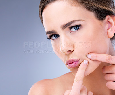 Buy stock photo Cropped shot of a young woman squeezing a pimple on her face against a grey background