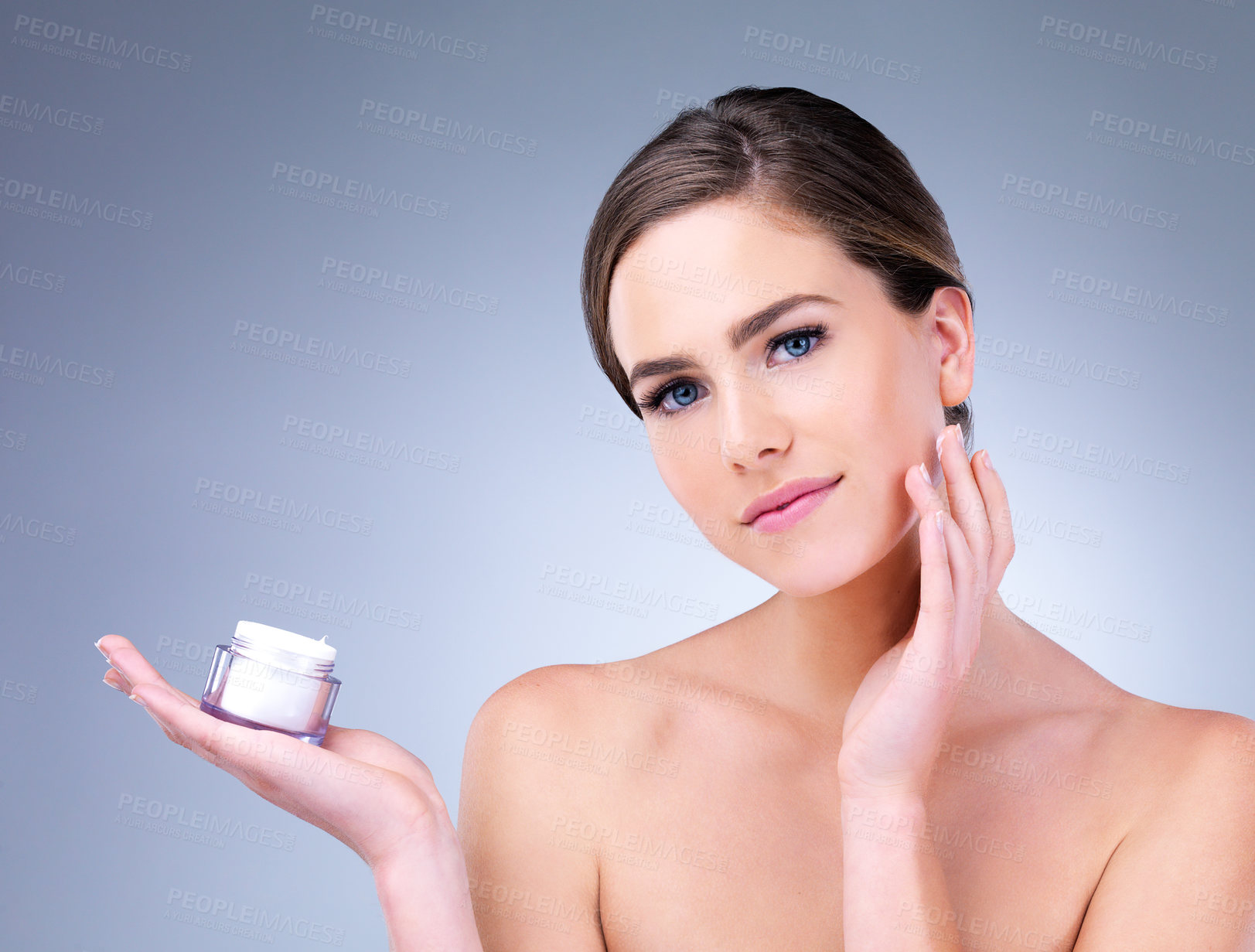 Buy stock photo Cropped shot of a young woman applying moisturizer to her face