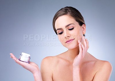Buy stock photo Cropped shot of a young woman applying moisturizer to her face