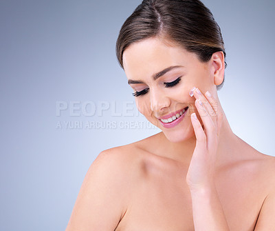 Buy stock photo Cropped shot of a young woman applying moisturizer to her face
