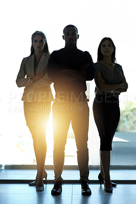 Buy stock photo Silhouette of a group of confident businesspeople standing together in an office