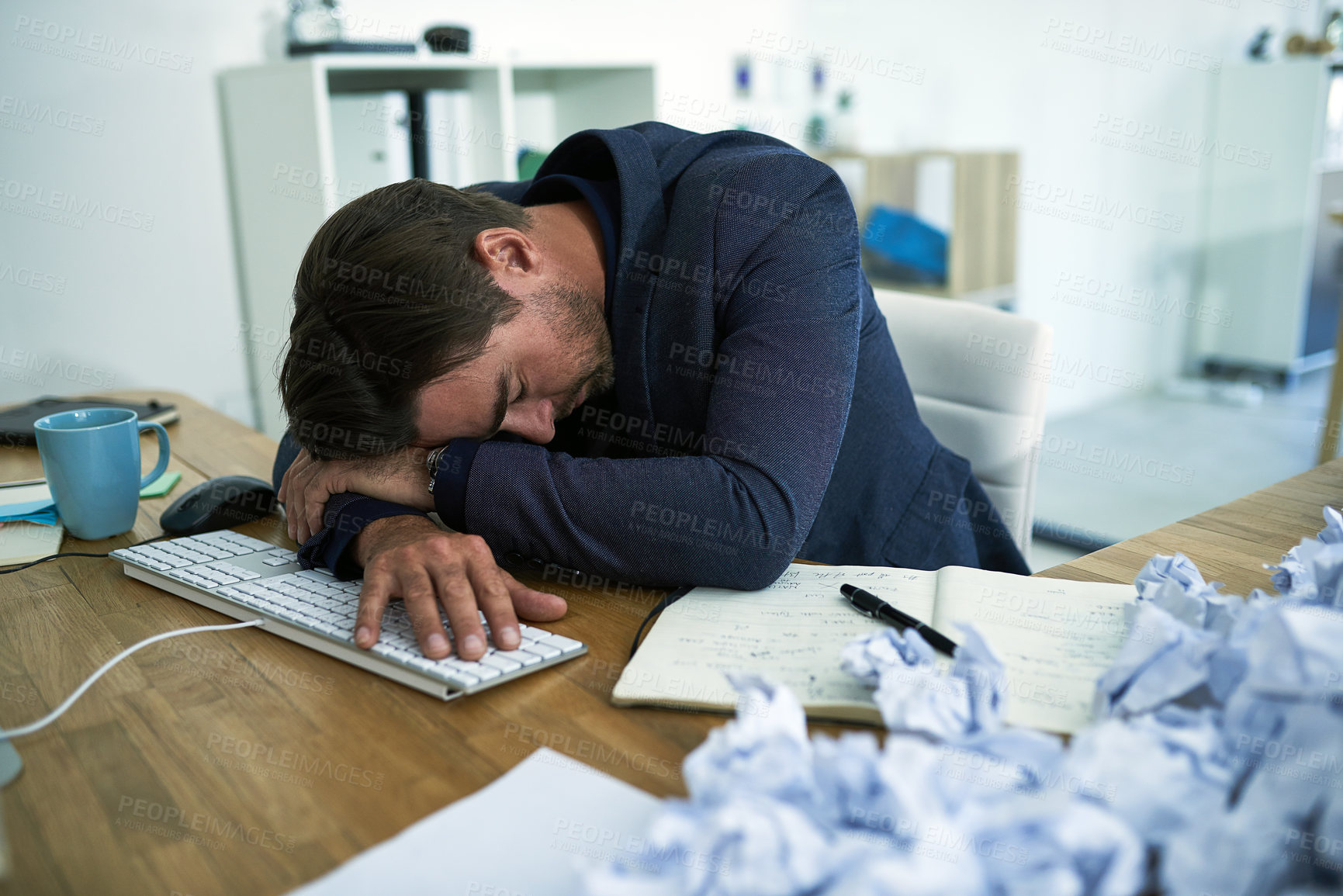 Buy stock photo Shot of a stressed out businessman passed out at his desk overwhelmed by paperwork