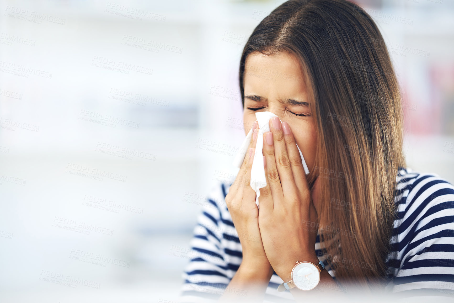 Buy stock photo Shot of a young woman with allergies sneezing into a tissue at home