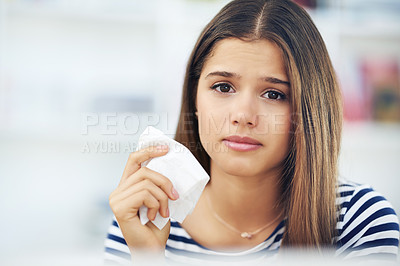 Buy stock photo Portrait of a young woman suffering from allergies holding a tissue at home