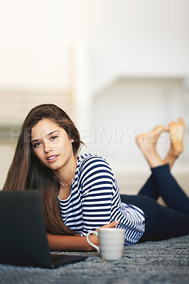 Buy stock photo Portrait of a young woman lying on the floor at home using a laptop