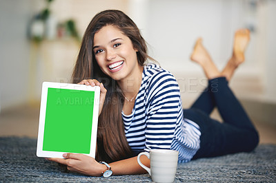 Buy stock photo Portrait of a smiling young woman lying on the floor at home holding up a digital tablet with a chroma key screen