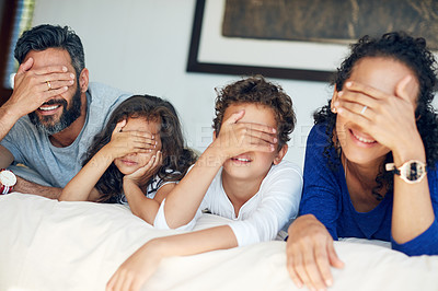 Buy stock photo Cropped shot of a family covering their eyes while lying down on a bed at home