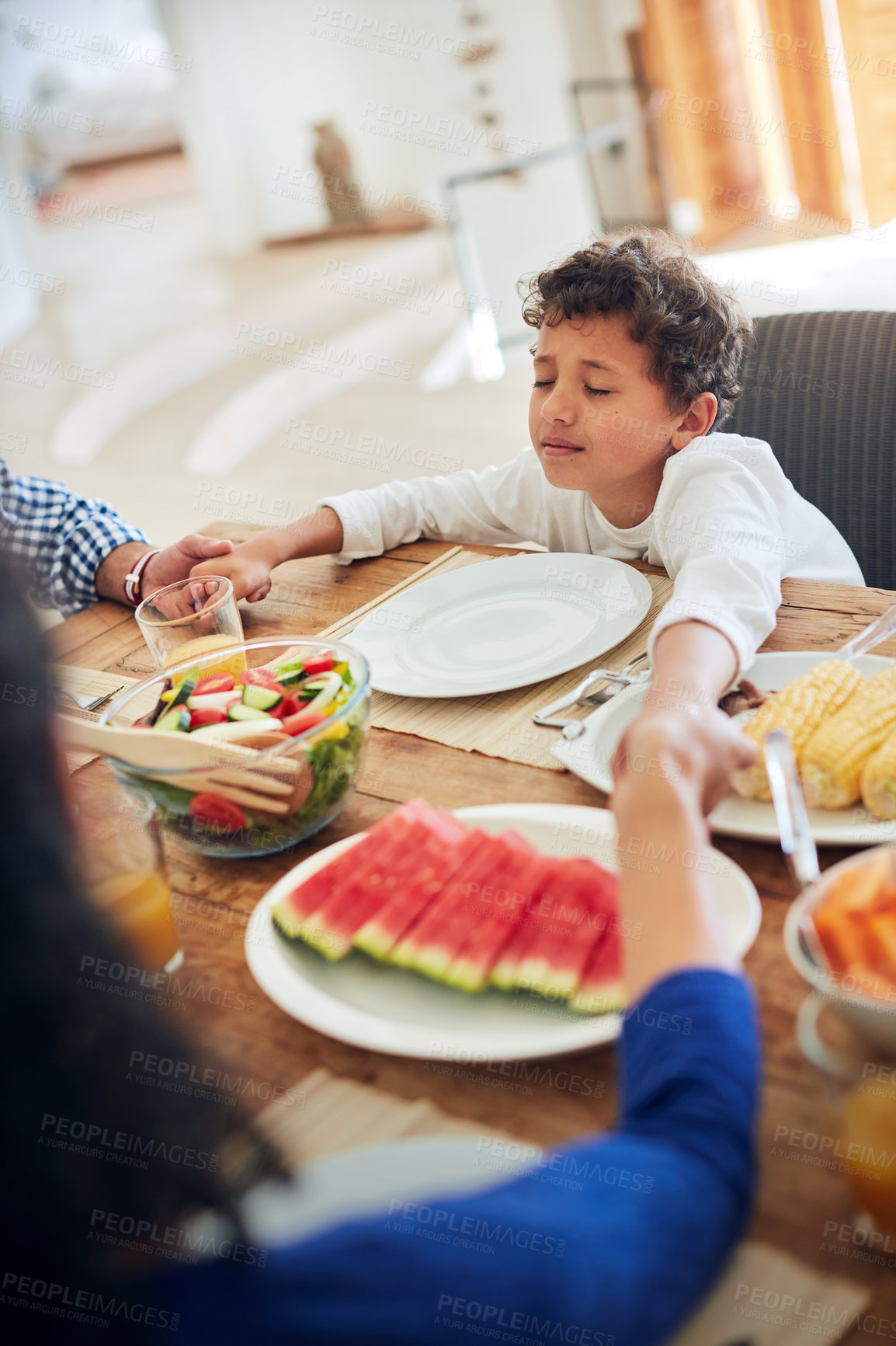 Buy stock photo Shot of a family praying together before enjoying a meal at the table