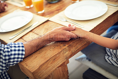 Buy stock photo Shot of an unidentifiable family praying together before enjoying a meal at the table