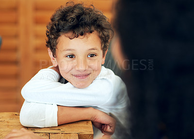 Buy stock photo Shot of a cute little boy looking at his mother while sitting at the table at home