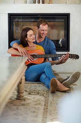 Buy stock photo Shot of a mature couple playing the guitar together at home