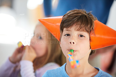 Buy stock photo Portrait of a cute little boy playing with a party horn at a birthday party