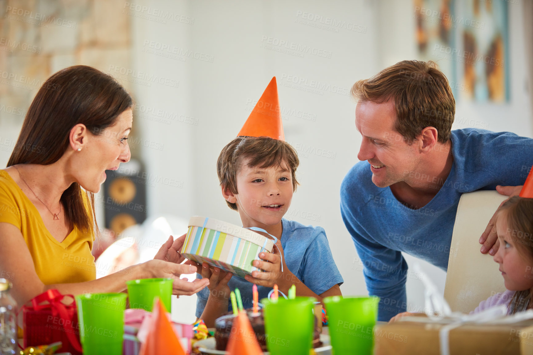 Buy stock photo Shot of a little boy opening his birthday presents surrounded by his family