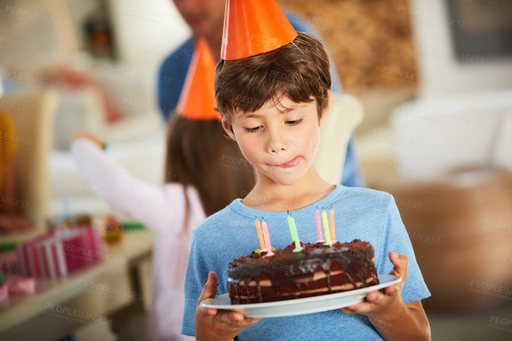 Buy stock photo Shot of a little boy holding a birthday cake and licking his lips in anticipation