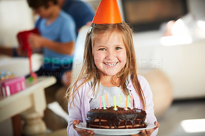 Buy stock photo Portrait of a happy little girl holding a birthday cake with her family in the background