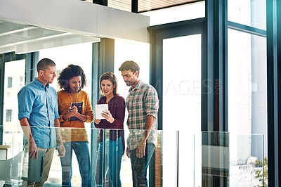 Buy stock photo Cropped shot of four young coworkers talking while looking at a digital tablet