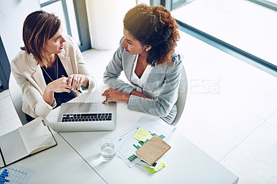 Buy stock photo Cropped shot of two corporate businesswomen working together on a laptop in an office