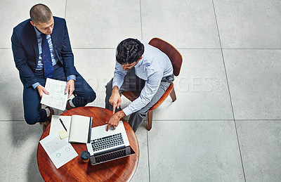 Buy stock photo High angle shot of two businessmen working together on a project in a modern office