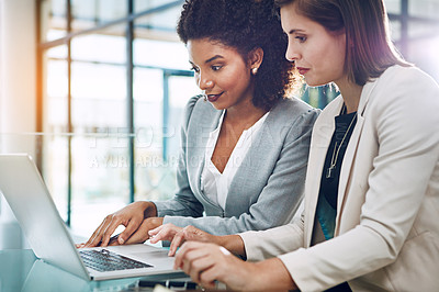 Buy stock photo Shot of two young businesswomen using a laptop together at work