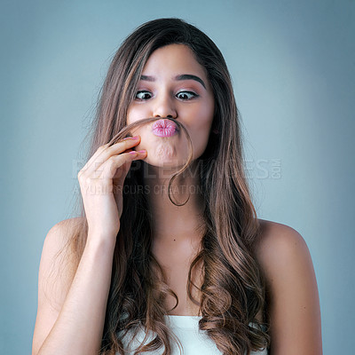 Buy stock photo Studio shot of a beautiful young woman playfully making a mustache with her hair