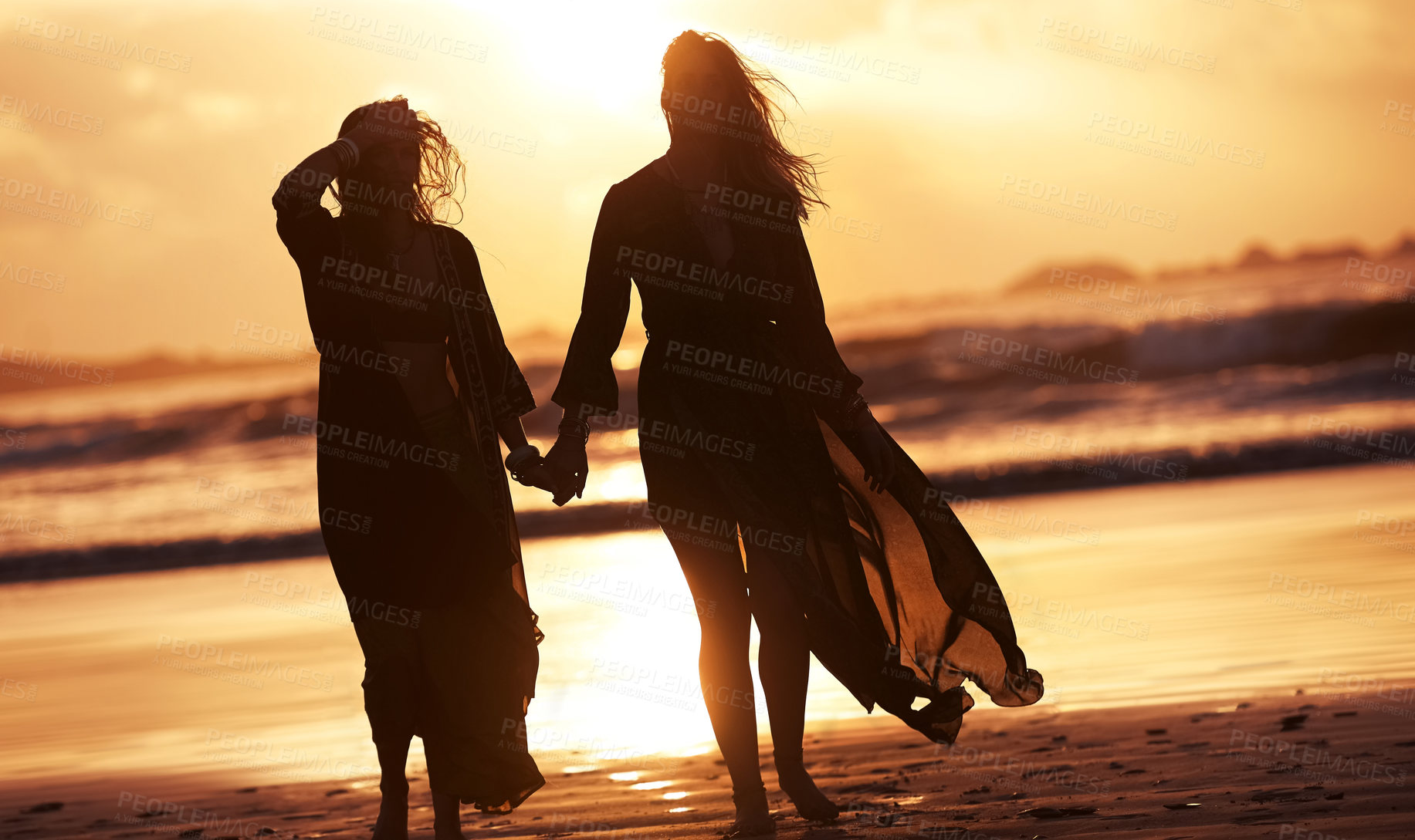 Buy stock photo Shot of two young women spending the day at the beach at sunset