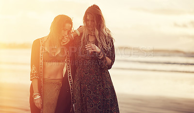 Buy stock photo Shot of two young women spending the day at the beach at sunset