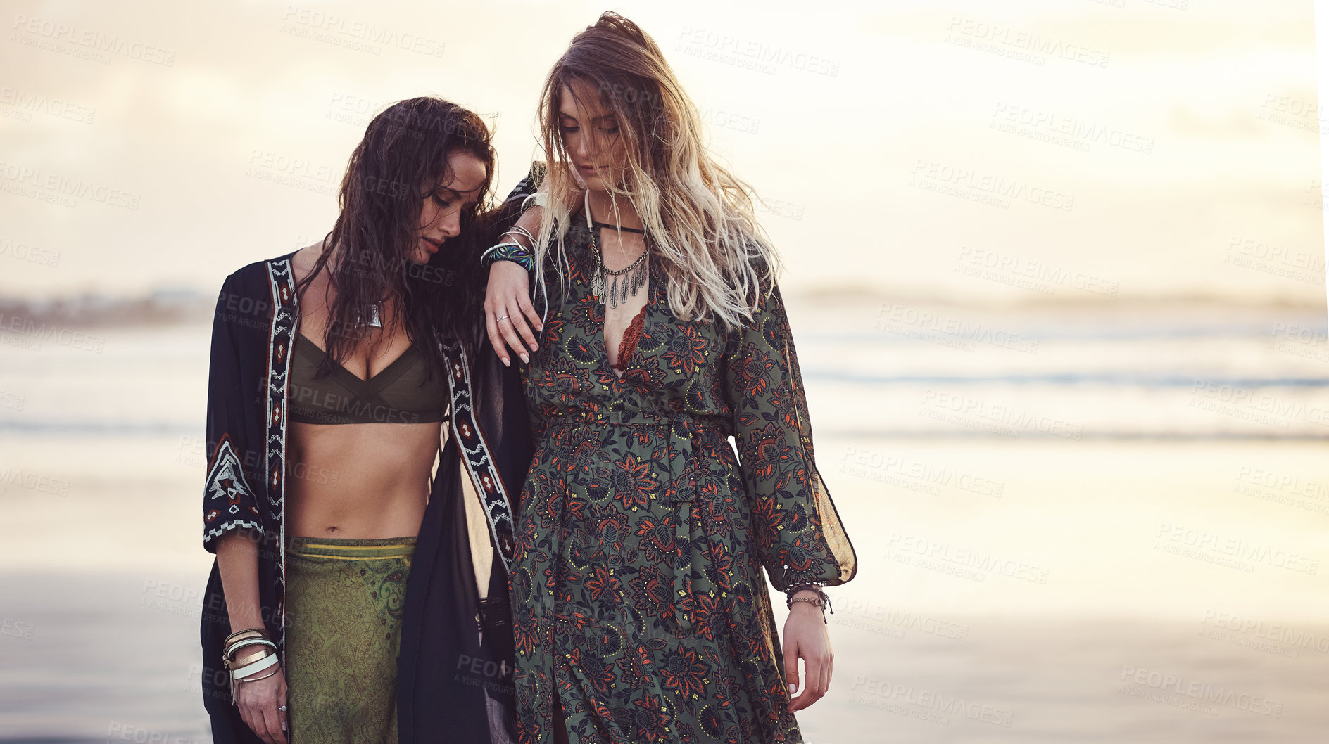 Buy stock photo Shot of two young women spending the day at the beach at sunset