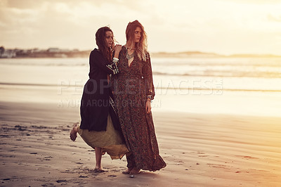 Buy stock photo Shot of two young women spending the day at the beach at sunset