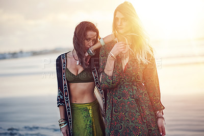 Buy stock photo Shot of two young women spending the day at the beach at sunset