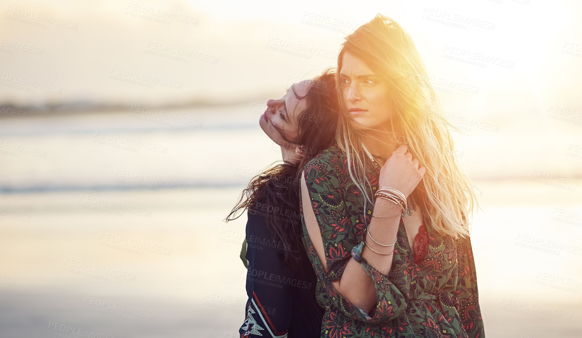 Buy stock photo Shot of two young women spending the day at the beach at sunset